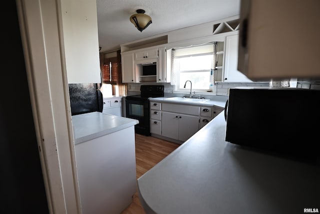 42060 County Highway 10, Nebo, IL 62355 - kitchen featuring black range with electric stovetop, white cabinetry, light wood finished floors, and light countertops