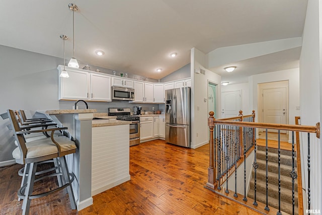 3 Megan Ct, Bloomington, IL 61705 - kitchen featuring appliances with stainless steel finishes, a peninsula, lofted ceiling, dark wood finished floors, and white cabinetry