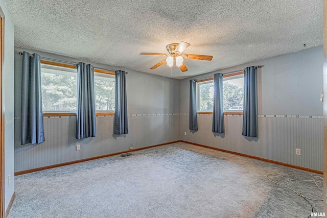913 N Flora Dr, Mount Pulaski, IL 62548 - empty room featuring healthy amount of natural light, ceiling fan, carpet flooring, and a textured ceiling