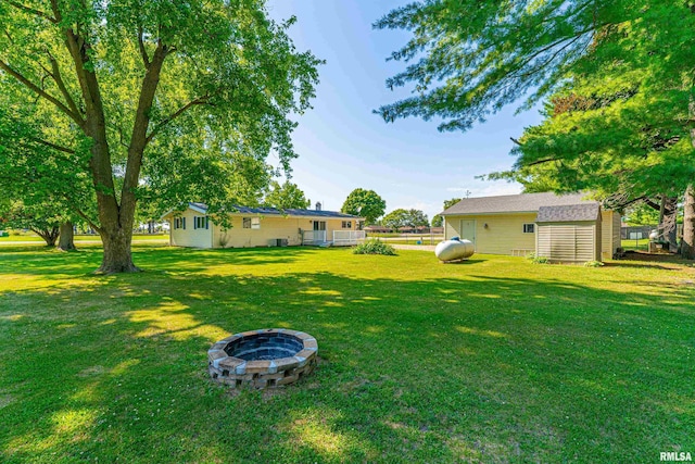 913 N Flora Dr, Mount Pulaski, IL 62548 - view of green lawn with an outdoor fire pit and a storage unit