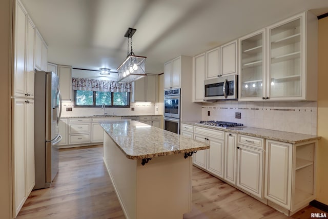 1220 Springdale S Dr, Quincy, IL 62305 - kitchen with stainless steel appliances, a kitchen island, light wood-style flooring, backsplash, and light stone counters