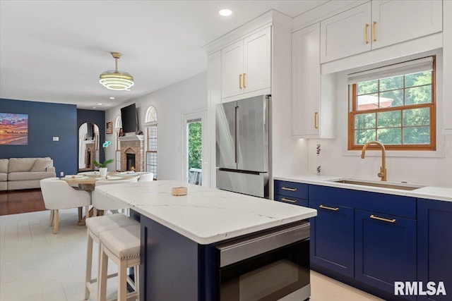 345 Country Towne Rd, Springfield, IL 62712 - kitchen featuring appliances with stainless steel finishes, blue cabinets, a center island, open floor plan, and white cabinetry