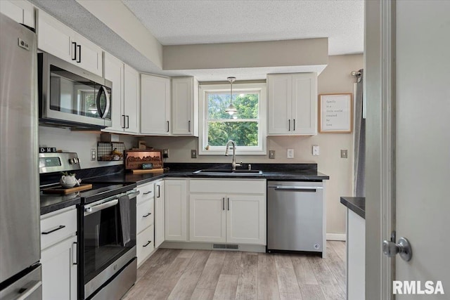 84 Chukar Dr, Chatham, IL 62629 - kitchen featuring appliances with stainless steel finishes, light wood-type flooring, dark countertops, white cabinets, and pendant lighting
