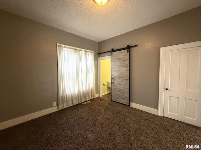 833 Willard St, Galesburg, IL 61401 - unfurnished bedroom with dark colored carpet, a textured ceiling, and a barn door