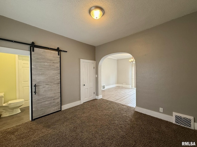 833 Willard St, Galesburg, IL 61401 - unfurnished bedroom featuring arched walkways, carpet flooring, ensuite bath, and a textured ceiling