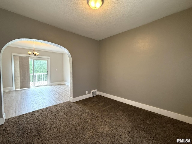 833 Willard St, Galesburg, IL 61401 - empty room with arched walkways, dark carpet, a chandelier, and a textured ceiling