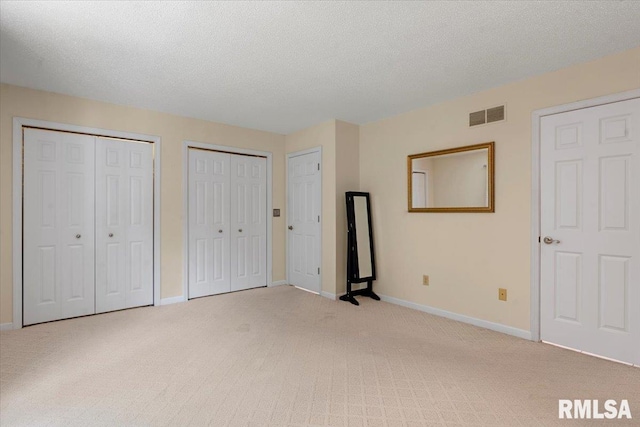 1009 Rickard Ct, Springfield, IL 62704 - unfurnished bedroom featuring light colored carpet, two closets, and a textured ceiling