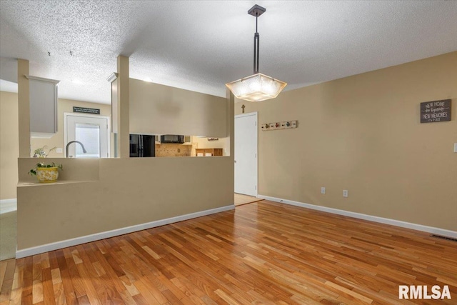 1009 Rickard Ct, Springfield, IL 62704 - kitchen featuring light wood-style floors, freestanding refrigerator, a textured ceiling, a peninsula, and hanging light fixtures