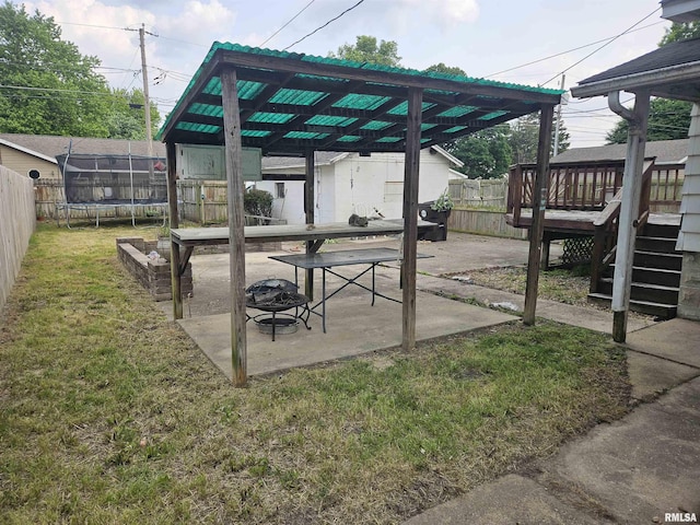 426 N Hamilton St, Lincoln, IL 62656 - fenced backyard featuring a trampoline, an outdoor fire pit, a patio area, a wooden deck, and stairs