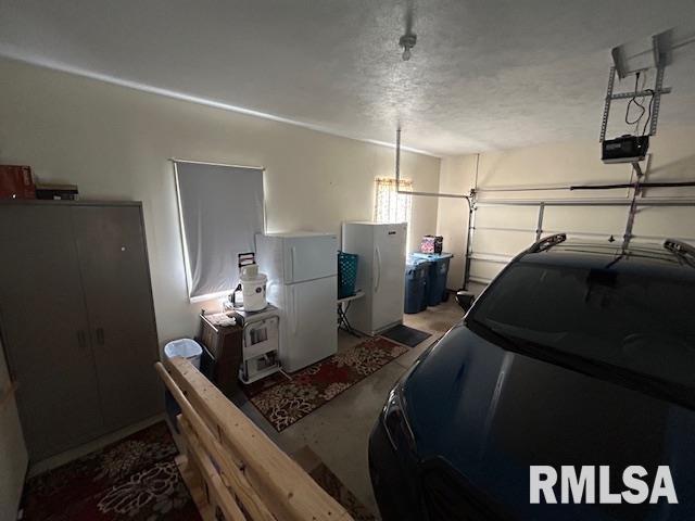 4424 Venetian Dr, Springfield, IL 62703 - garage featuring freestanding refrigerator and a garage door opener