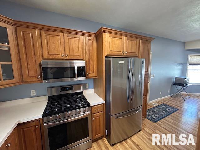 4424 Venetian Dr, Springfield, IL 62703 - kitchen featuring stainless steel appliances, brown cabinetry, light countertops, and light wood-style flooring