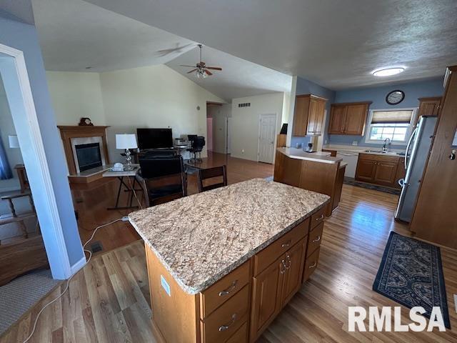 4424 Venetian Dr, Springfield, IL 62703 - kitchen with freestanding refrigerator, a kitchen island, light wood-style flooring, open floor plan, and vaulted ceiling