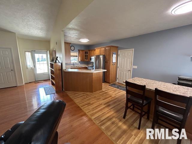 4424 Venetian Dr, Springfield, IL 62703 - kitchen with a peninsula, brown cabinets, glass insert cabinets, light countertops, and light wood-style flooring