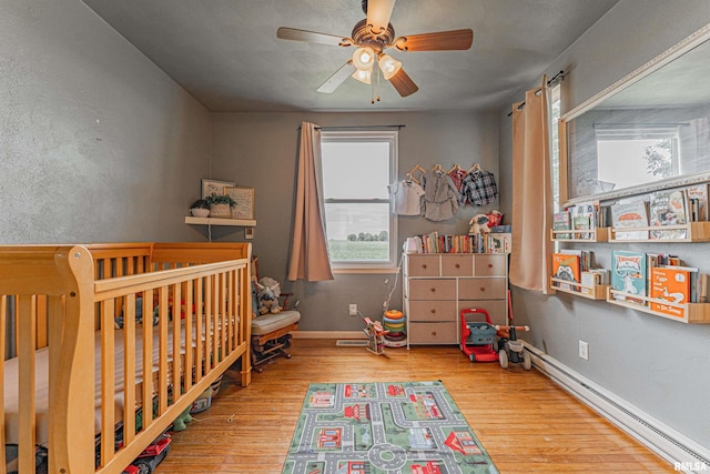 209 N 2nd St N, Easton, IL 62633 - bedroom featuring wood finished floors, baseboard heating, a nursery area, and ceiling fan