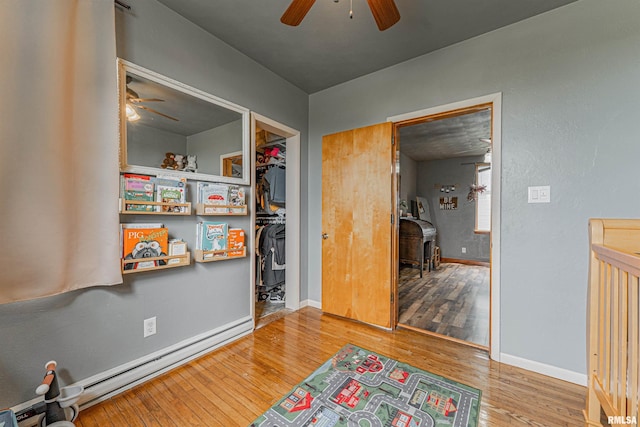 209 N 2nd St N, Easton, IL 62633 - bedroom featuring a baseboard radiator, a wood stove, wood finished floors, and a ceiling fan