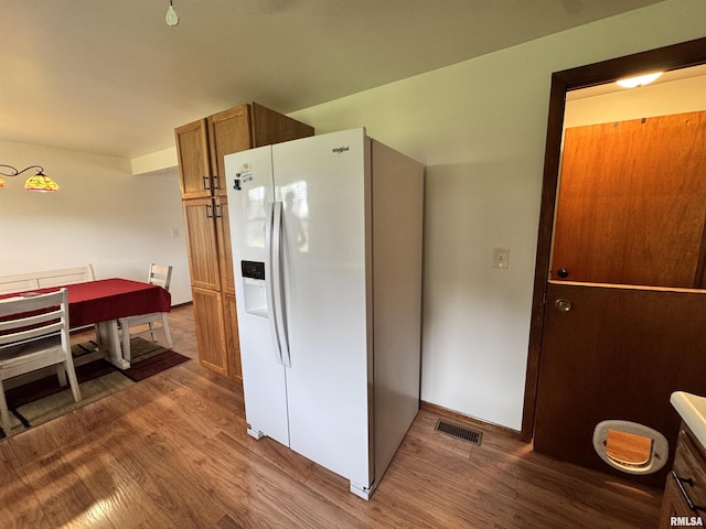 1275 Sunview Dr, Canton, IL 61520 - kitchen featuring white fridge with ice dispenser, wood finished floors, and brown cabinetry