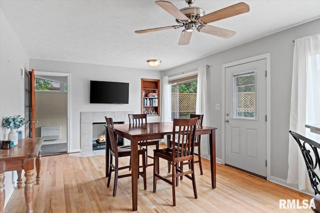 14 Beachview Ln, Springfield, IL 62712 - dining area featuring light wood-type flooring, a ceiling fan, a tiled fireplace, and a textured ceiling