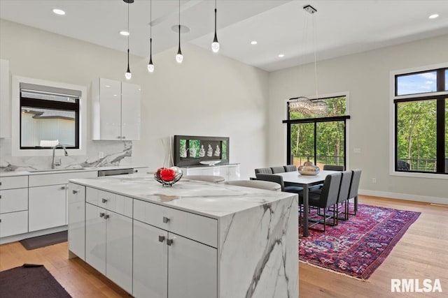 2004 Grants Pond, Chatham, IL 62629 - kitchen featuring a kitchen island, white cabinets, light wood-style flooring, light stone countertops, and pendant lighting