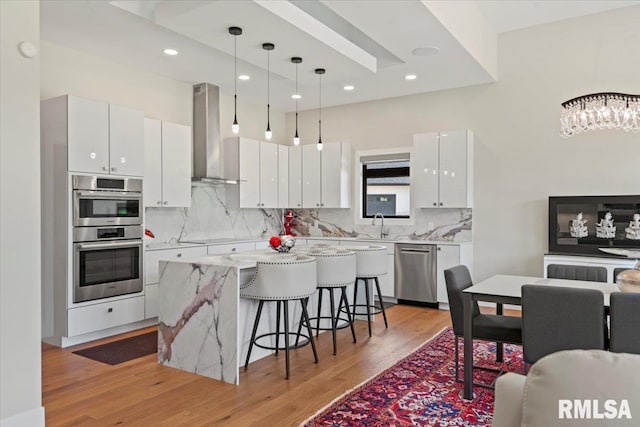 2004 Grants Pond, Chatham, IL 62629 - kitchen featuring wall chimney exhaust hood, appliances with stainless steel finishes, a kitchen breakfast bar, light wood-style flooring, and recessed lighting