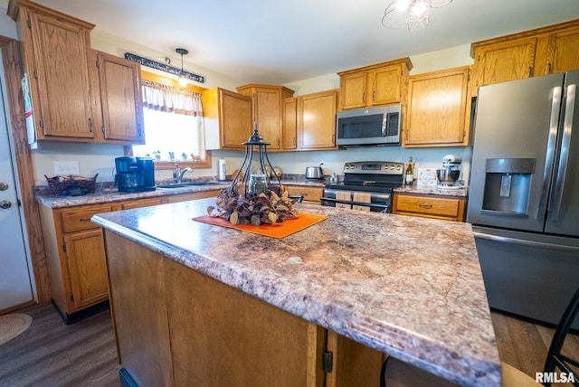 23490 E Maple Rd, Bluford, IL 62814 - kitchen featuring appliances with stainless steel finishes, dark wood-style flooring, pendant lighting, a kitchen island, and brown cabinets
