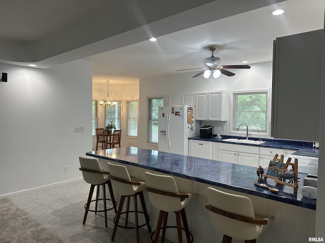 4004 Abbey Ridge St, Quincy, IL 62305 - kitchen with white cabinets, white fridge with ice dispenser, healthy amount of natural light, a breakfast bar area, and recessed lighting