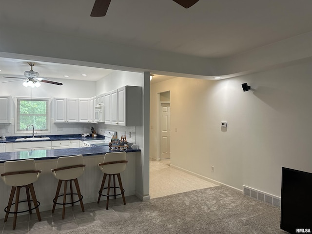 4004 Abbey Ridge St, Quincy, IL 62305 - kitchen with a ceiling fan, a breakfast bar, dark countertops, white appliances, and recessed lighting