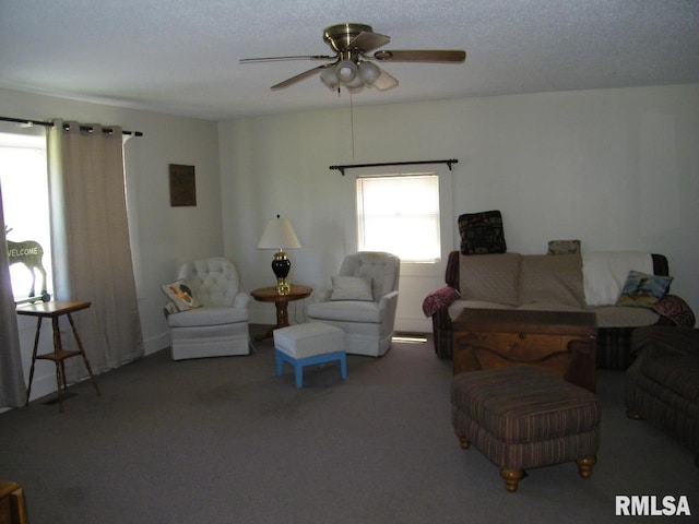 living room with ceiling fan, dark colored carpet, and a textured ceiling