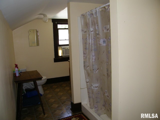 bathroom with tile floors, toilet, and vaulted ceiling