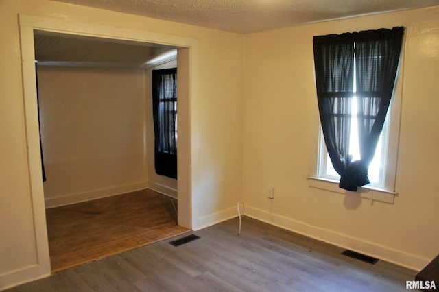 empty room featuring dark hardwood / wood-style floors and a textured ceiling