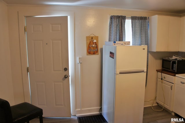 kitchen with white fridge, white cabinetry, and dark hardwood / wood-style flooring