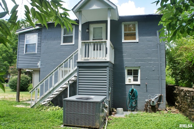 rear view of house with central AC and a yard