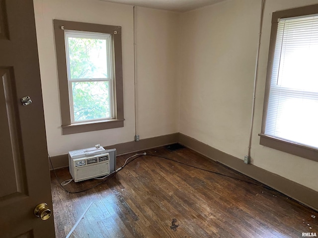 spare room featuring plenty of natural light, dark hardwood / wood-style floors, and an AC wall unit