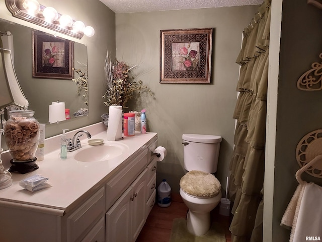 bathroom featuring a textured ceiling, large vanity, and toilet