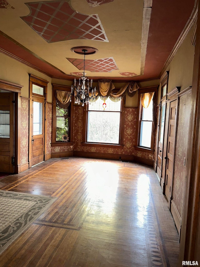 unfurnished dining area featuring ornamental molding, dark wood-type flooring, and an inviting chandelier