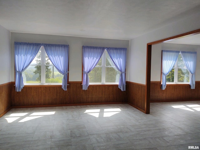 unfurnished room with wood walls and light tile floors