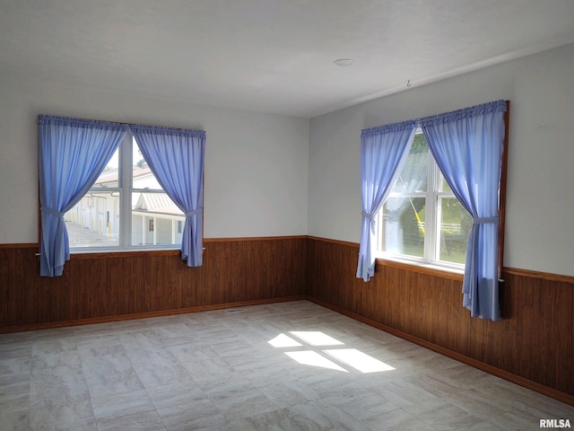 empty room with wood walls and light tile floors