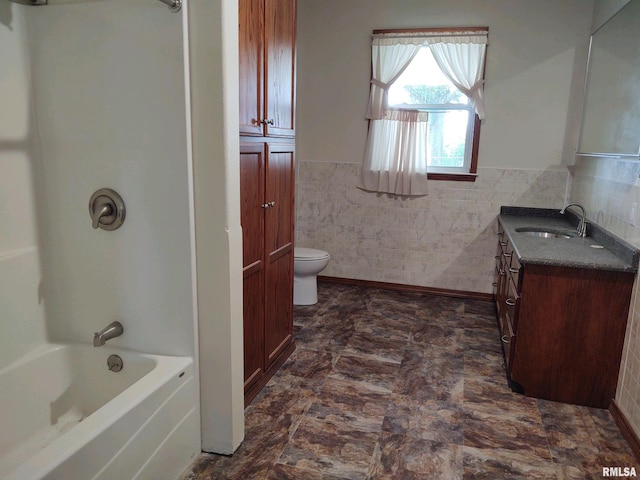 bathroom with tile flooring, toilet, vanity, and tile walls