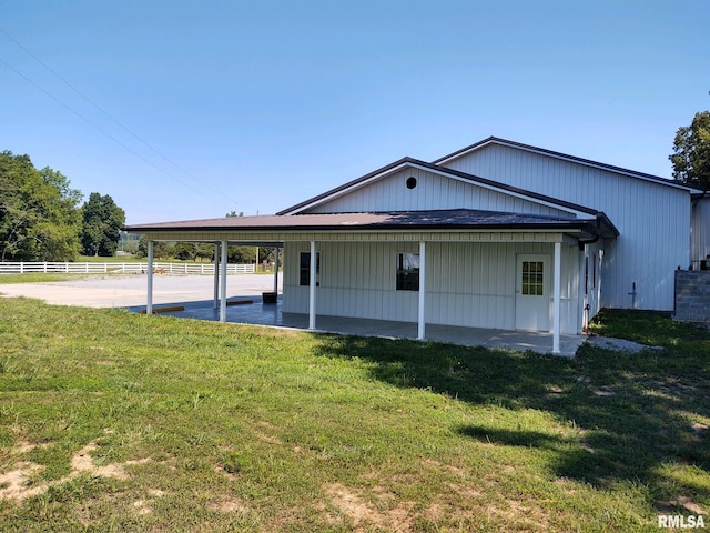 rear view of house featuring a lawn and a carport