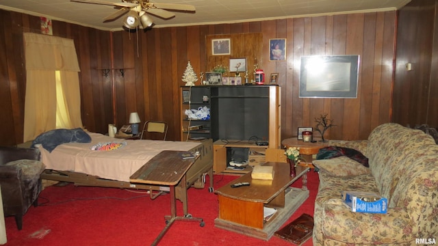 carpeted bedroom featuring ceiling fan, ornamental molding, and wood walls