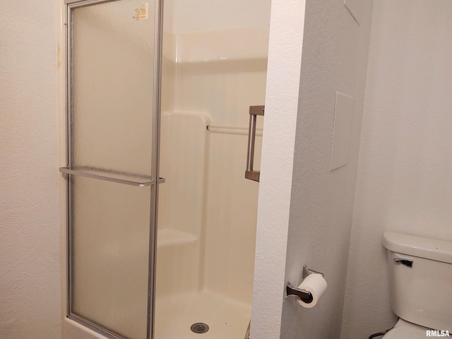 bathroom with toilet and a shower with shower door