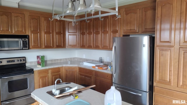 kitchen with ornamental molding, appliances with stainless steel finishes, brown cabinetry, and a sink