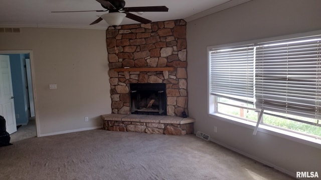 unfurnished living room with a stone fireplace, carpet flooring, visible vents, baseboards, and crown molding