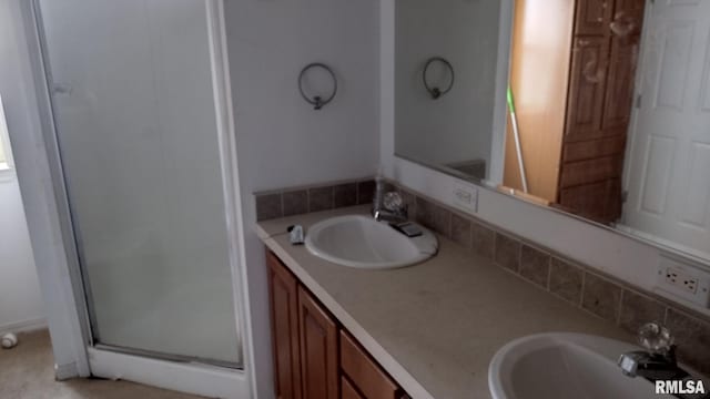 bathroom with double vanity, a shower stall, and a sink