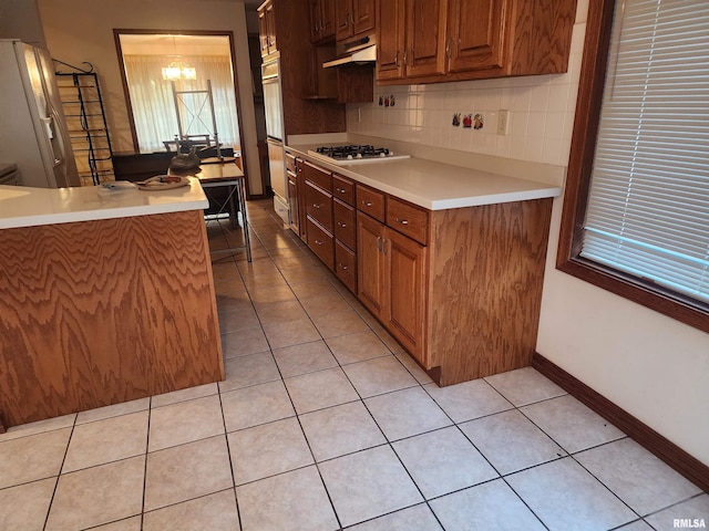 kitchen with white appliances, a notable chandelier, light tile patterned flooring, and tasteful backsplash