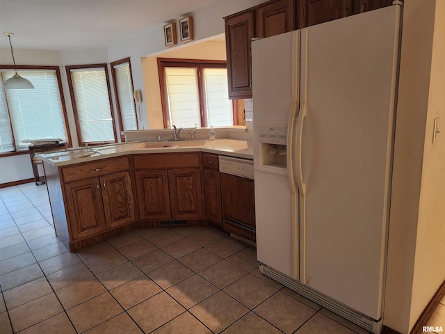 kitchen featuring sink, dishwashing machine, light tile patterned floors, white fridge with ice dispenser, and hanging light fixtures