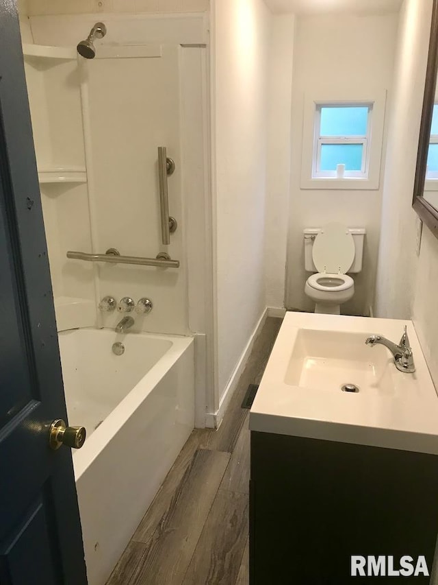 full bathroom featuring washtub / shower combination, wood-type flooring, vanity, and toilet