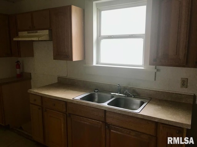 kitchen with a wealth of natural light, custom range hood, and sink