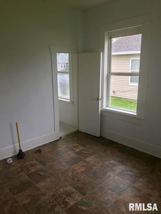 unfurnished room featuring dark tile flooring