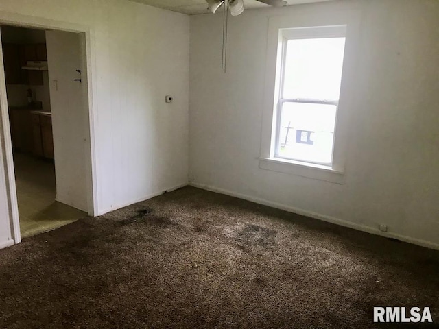 spare room with dark colored carpet and ceiling fan