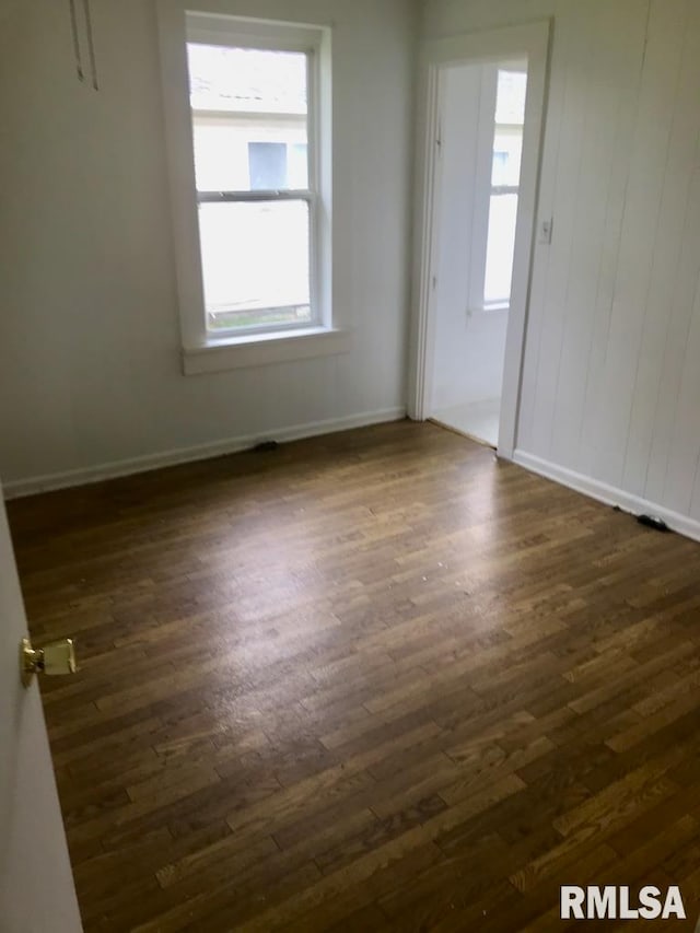 empty room featuring a healthy amount of sunlight and dark hardwood / wood-style flooring